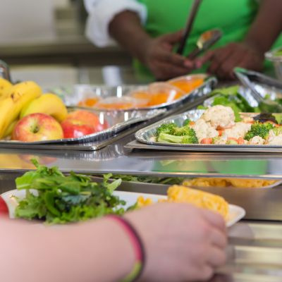 KI generiert: Essensausgabe mit frischem Obst, Gemüse und Salat in einer Cafeteria.