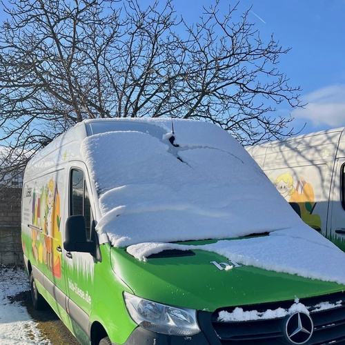 KI generiert: Ein grün-weißer Lieferwagen mit Schnee bedeckt. Text: "bio-liese.de".