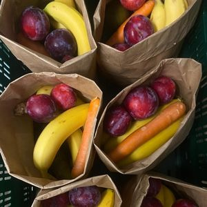 KI generiert: Papiertüten mit Bananen, Pflaumen und Karotten drin.
