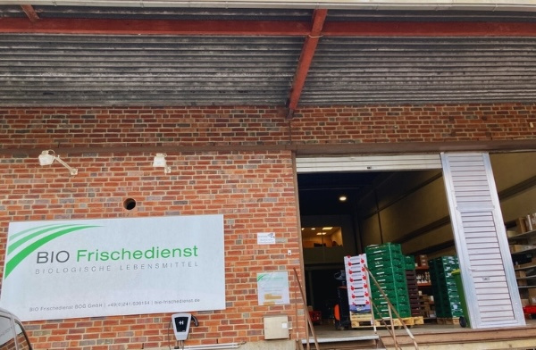 KI generiert: Offenes Lager mit Paletten und ein Schild: "BIO Frischedienst Biologische Lebensmittel".