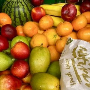 KI generiert: Eine Auswahl an buntem Obst, darunter Melone, Orangen, Äpfel und Bananen. Beutel mit unleserlichem Text.