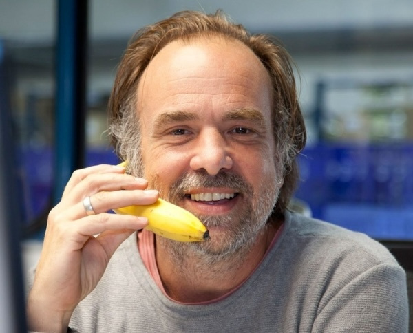 KI generiert: Mann hält eine Banane ans Ohr wie ein Telefon, lächelt.
