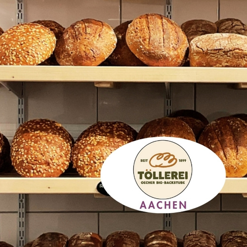 KI generiert: Regale voller frisch gebackener Brote; Logo: TÖLLEREI Oecher Bio-Backstube, Aachen.
