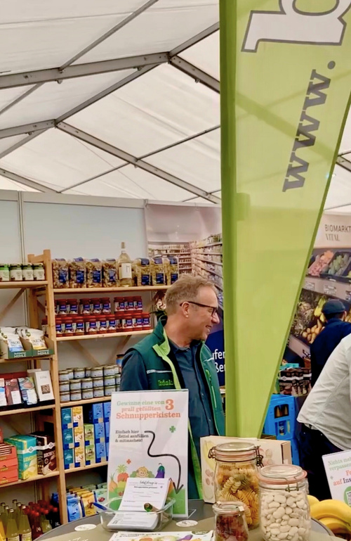 KI generiert: Verkaufsstand mit Lebensmitteln und Werbung für "3 gefüllte Schnupperkisten".