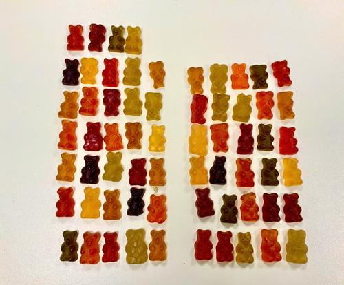 KI generiert: Gesamtansicht von Gummibärchen in verschiedenen Farben, die in Reihen auf einem weißen Hintergrund angeordnet sind.